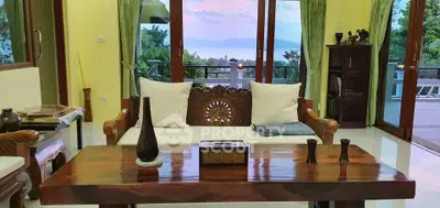 Elegant living room with wooden furniture and stunning ocean view through large windows.