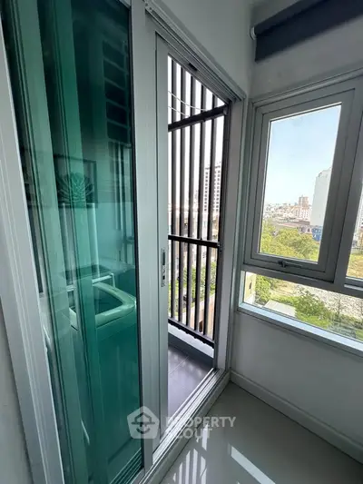 Modern apartment with balcony and city view, featuring sleek sliding glass doors and large windows.