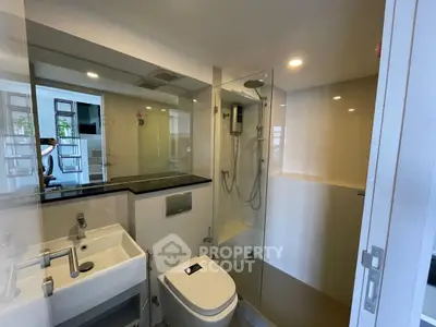 Modern bathroom with glass shower and sleek fixtures in a contemporary apartment.