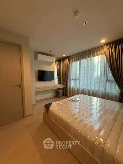 Modern bedroom with large window and wall-mounted TV in a stylish apartment.
