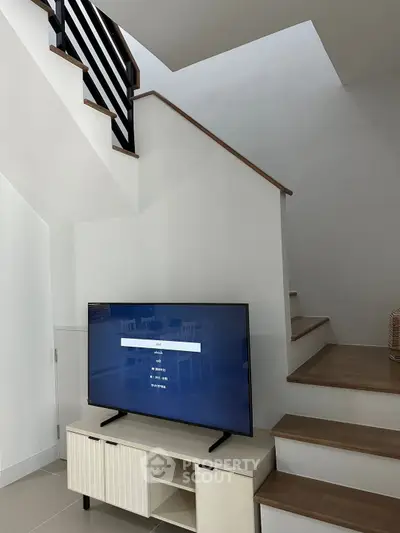 Modern living room with stylish staircase and TV setup, perfect for contemporary living.