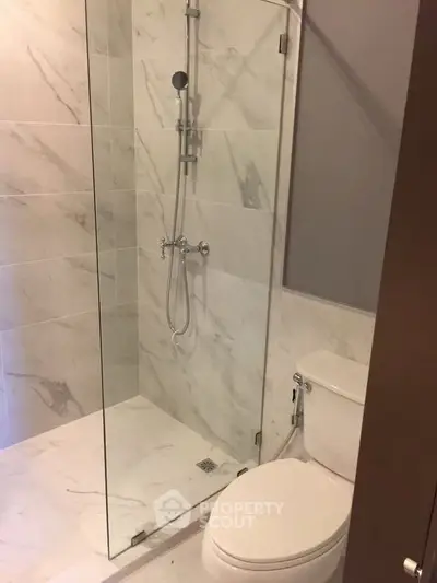 Modern bathroom with elegant marble tiles and glass shower enclosure