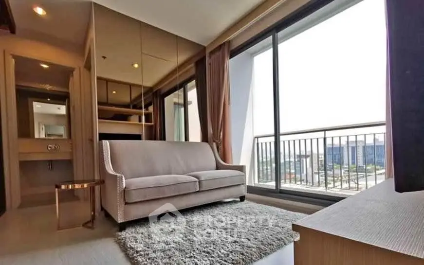 Modern living room with large windows and balcony offering city views, featuring a stylish sofa and cozy rug.