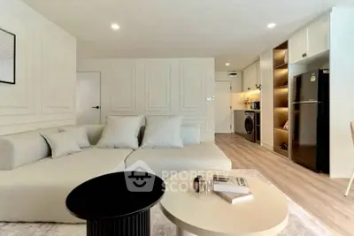 Modern living room with sleek design, cozy sofa, and integrated kitchen appliances.