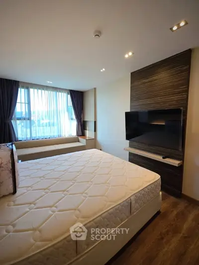 Modern bedroom with large window and mounted TV, featuring elegant decor and natural light.