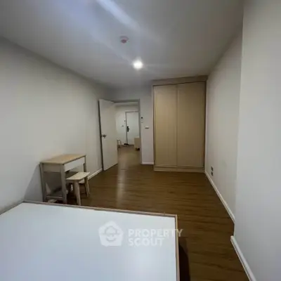 Spacious bedroom with wooden flooring and built-in wardrobe in modern apartment.
