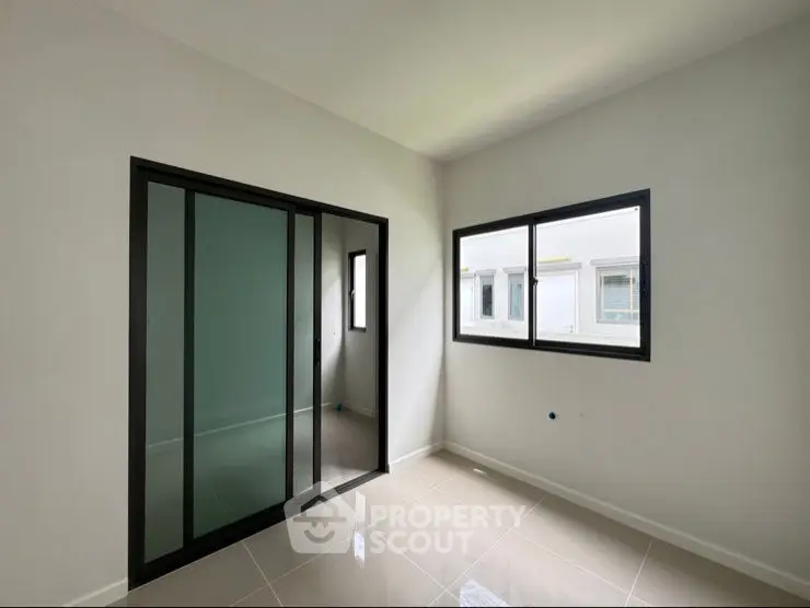 Modern minimalist room with sliding glass door and large windows, perfect for natural light.