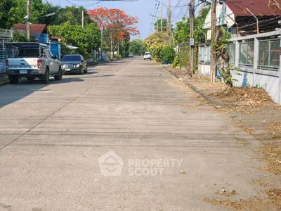 Quiet residential street with parked cars and lush greenery, ideal for peaceful living.