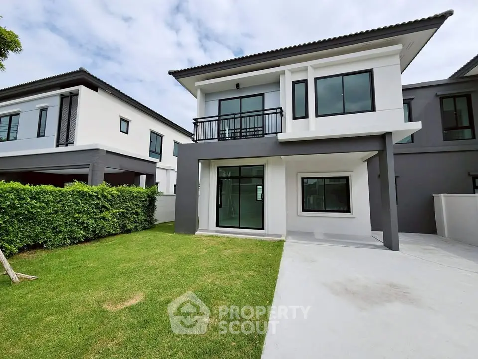 Modern two-story house with sleek design and spacious lawn in a suburban neighborhood.