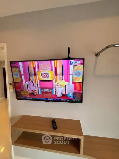 Modern living room with wall-mounted TV and sleek wooden shelf