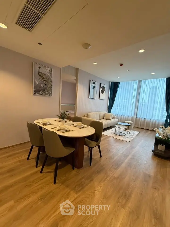 Spacious modern living room with elegant dining area and large windows offering city views.