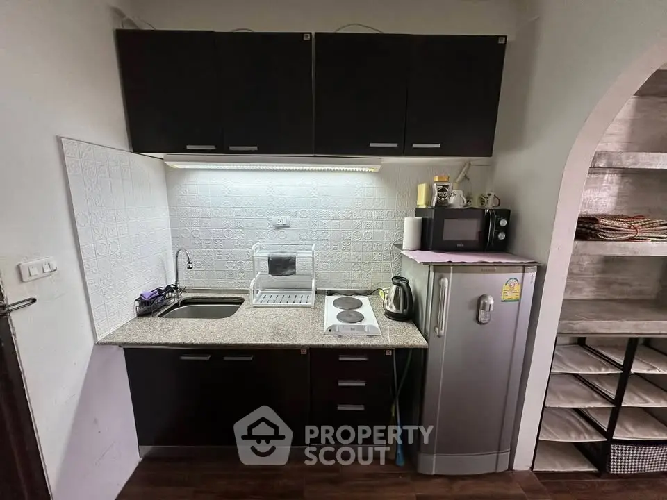 Compact kitchen with dark cabinets, granite countertop, and modern appliances