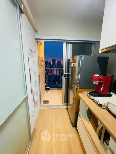 Modern kitchen with balcony view, featuring sleek appliances and wooden flooring.