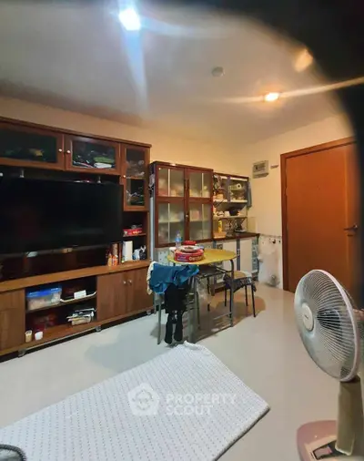 Cozy living room with wooden cabinets and modern TV setup, perfect for relaxation and entertainment.