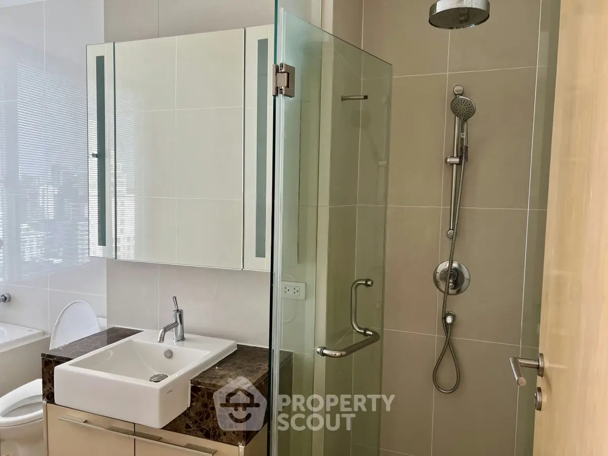 Modern bathroom with glass shower and sleek vanity in a contemporary apartment.