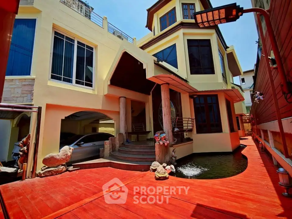 Stunning multi-level home with unique architecture and vibrant red deck, featuring a serene water feature.