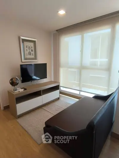 Cozy living room with modern TV setup and large window for natural light.