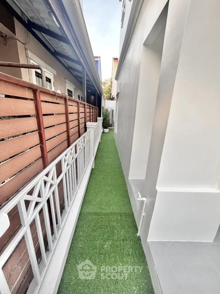 Narrow outdoor passage with artificial grass and modern fencing