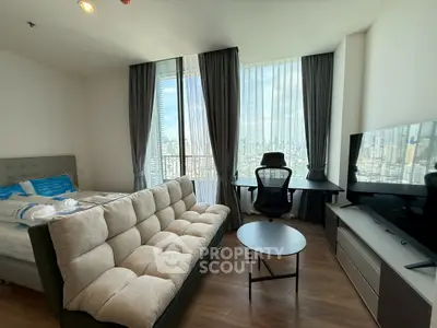 Modern studio apartment with city view, featuring a cozy sofa, bed, and work desk by large windows.