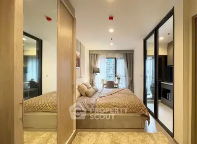Modern bedroom with large bed, mirrored wardrobe, and city view from window.