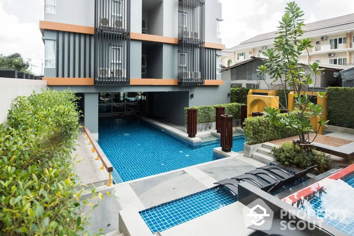 Modern residential complex with a stunning communal swimming pool, surrounded by lush greenery and stylish outdoor seating areas.