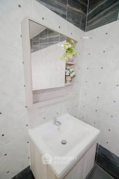 Modern bathroom with stylish sink and mirror, featuring elegant tile design and floral accents.