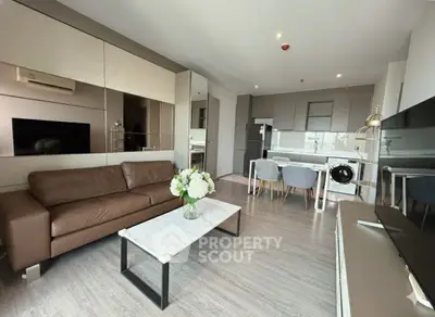 Modern living room with open kitchen, featuring sleek furniture and stylish decor in a contemporary apartment.