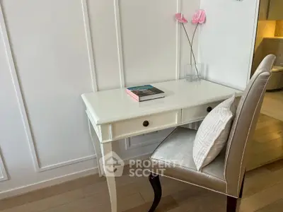 Elegant study nook with white desk, plush chair, and decorative accents in modern apartment.