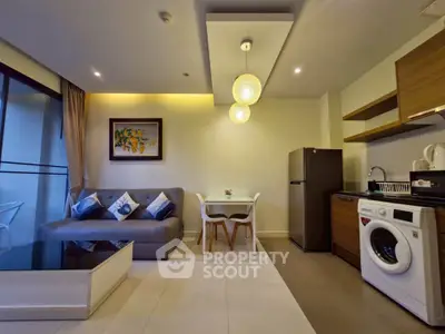 Modern living room with open kitchen, featuring stylish decor and appliances in a cozy apartment setting.
