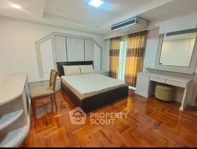 Spacious bedroom with elegant wooden flooring and modern furnishings