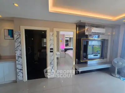 Modern living room with marble accents and sleek TV setup, leading to a stylish bedroom.