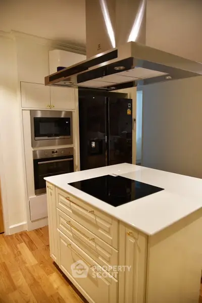Modern kitchen with sleek appliances and island cooktop in stylish apartment.