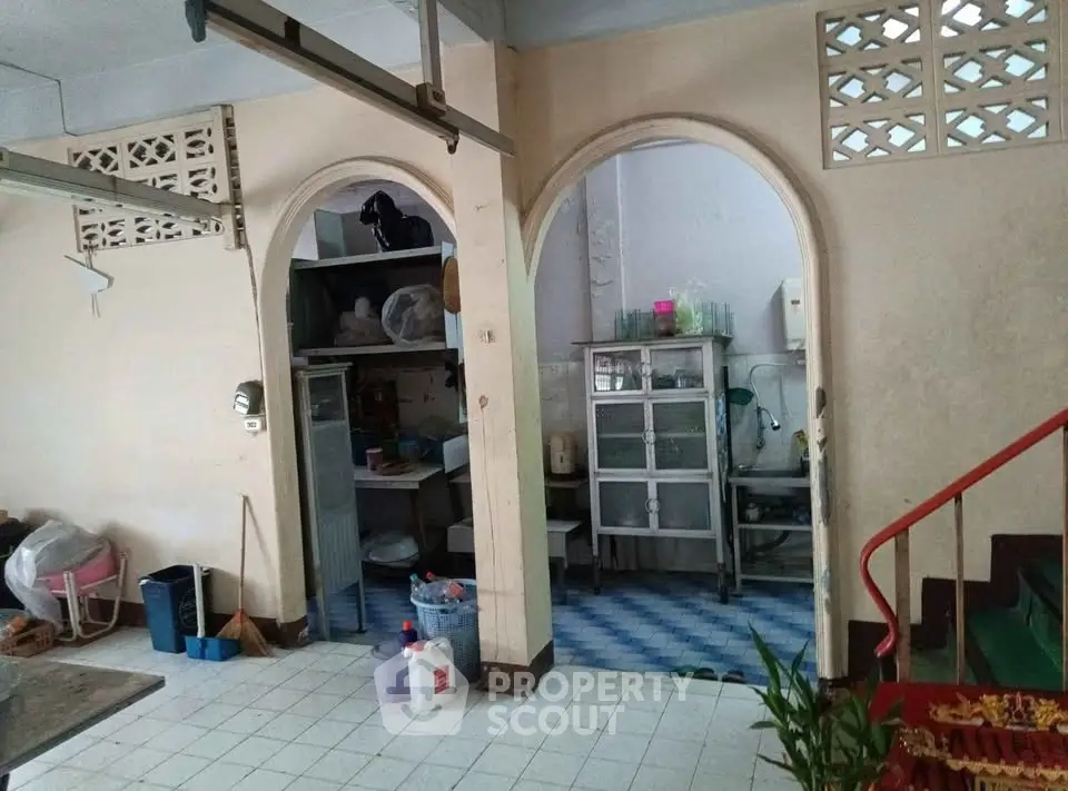 Charming vintage kitchen with arched doorways and tiled floor, perfect for renovation enthusiasts.