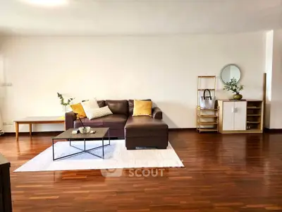 Spacious living room with modern decor and wooden flooring, featuring a stylish sofa and elegant coffee table.