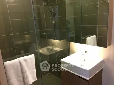 Modern bathroom with glass shower and sleek vanity in contemporary apartment.