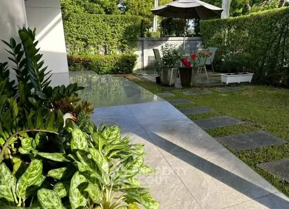 Charming garden with lush greenery and patio seating area, perfect for outdoor relaxation.