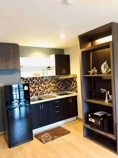 Modern kitchen with stylish cabinetry and mosaic backsplash in cozy apartment.