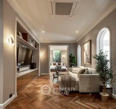 Luxurious living room with elegant herringbone flooring and modern decor, leading to a cozy bedroom.
