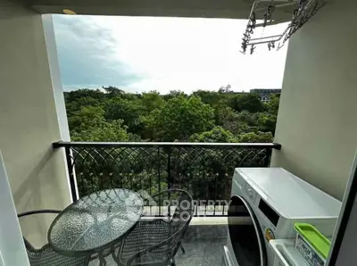 Charming balcony with lush green view, outdoor seating, and washing machine for convenience.