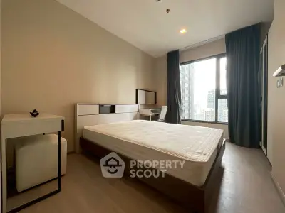 Modern bedroom with city view, featuring a sleek bed and study desk.