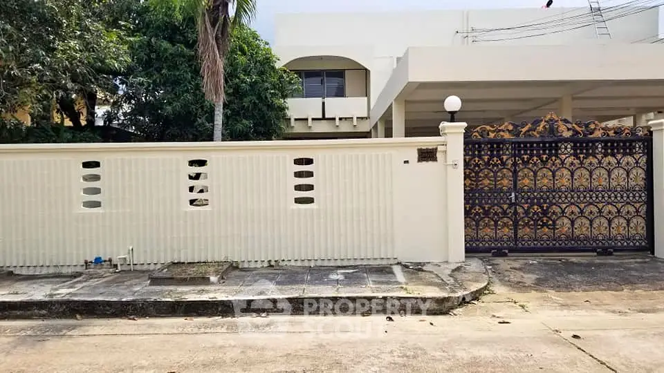 Elegant gated entrance of a modern home with decorative ironwork and privacy wall.