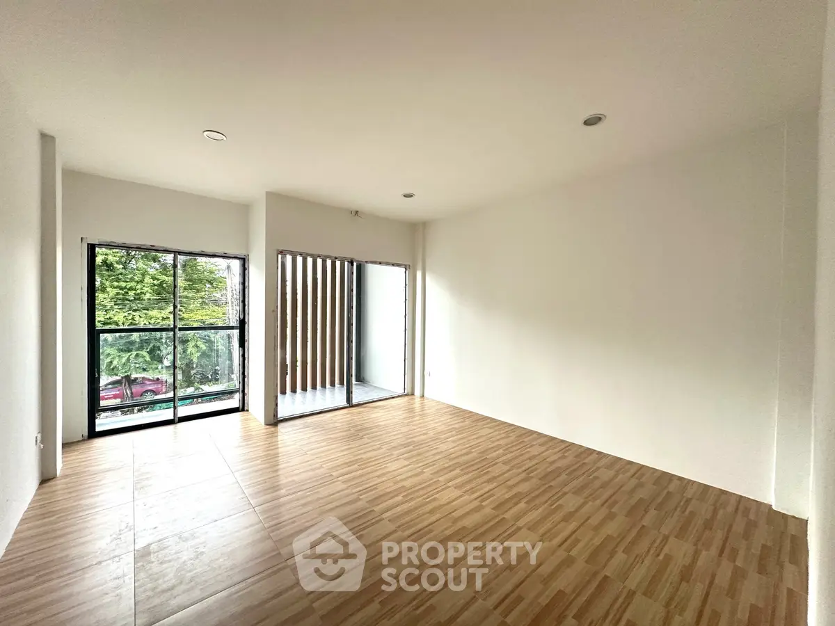 Spacious empty room with large windows and wooden flooring, perfect for customization.