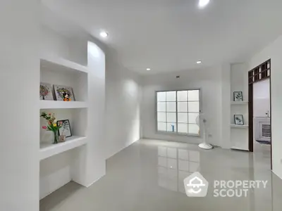 Spacious minimalist living room with built-in shelves and large window