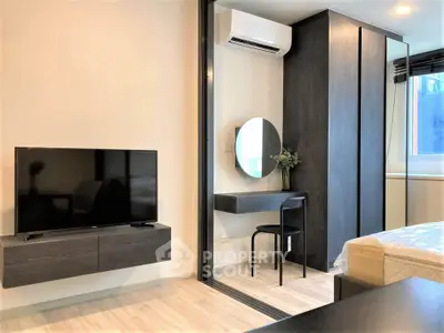 Modern bedroom with sleek furniture, wall-mounted TV, and stylish vanity area.