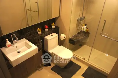 Modern bathroom with glass shower, sleek sink, and elegant decor in a contemporary home.