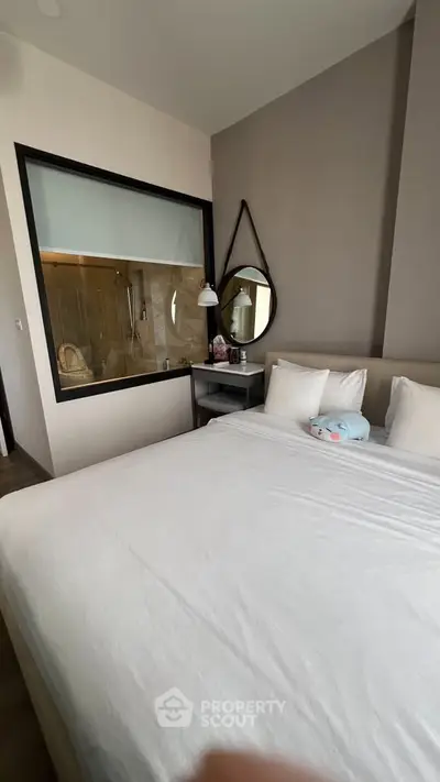 Modern bedroom with large bed and unique bathroom window feature