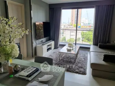 Modern living room with large window and city view, featuring stylish furniture and decor.