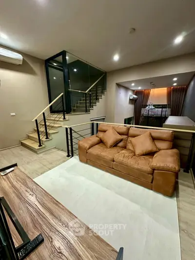 Modern living room with stylish staircase and cozy brown sofa in a contemporary home