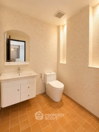 Spacious modern bathroom with elegant fixtures and warm tile flooring.