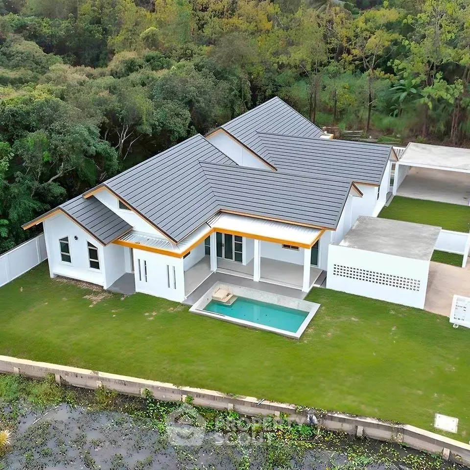 Stunning modern home with sleek roof design and private pool in lush green surroundings.